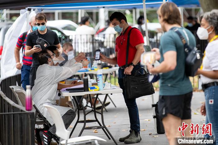 资料图：当地时间7月26日，美国纽约曼哈顿一处猴痘疫苗接种点，工作人员为民众验证预约信息。 中新社记者 廖攀 摄