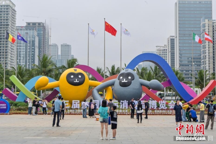 图为民众在海南国际会展中心外摆放的消博会主题广告前拍照留影。中新社记者 骆云飞 摄